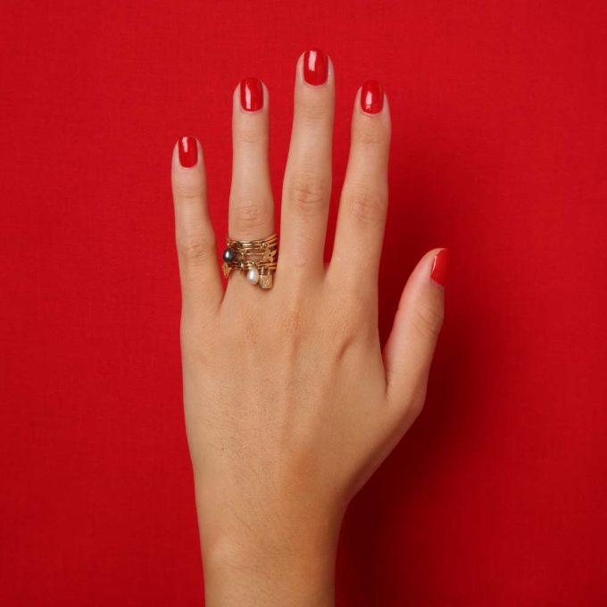 main sur fond rouge avec bague Louis Vuitton d'occasion