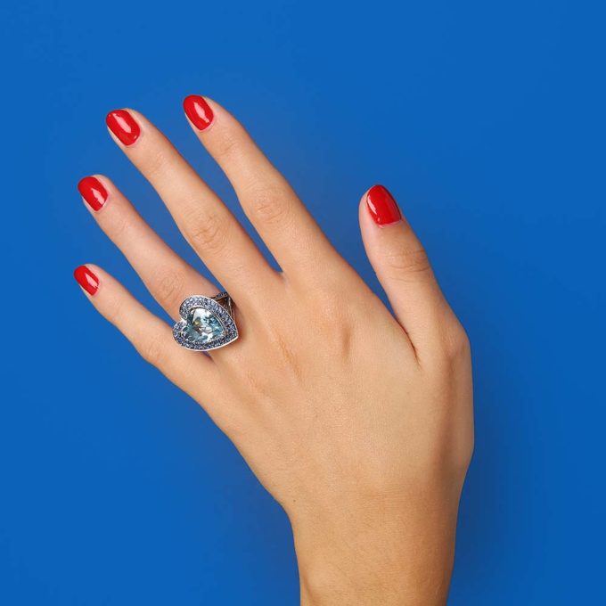 main sur fond bleu avec bague Mauboussin d'occasion